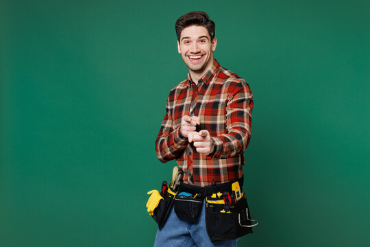 Young happy employee laborer handyman man wear red shirt point index finger camera on you isolated on plain green background. Instruments accessories for renovation apartment room Repair home concept