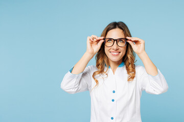 Female smiling happy doctor woman wearing white medical gown suit glasses work in hospital clinic office look overhead on area isolated on plain blue background studio. Health care medicine concept.