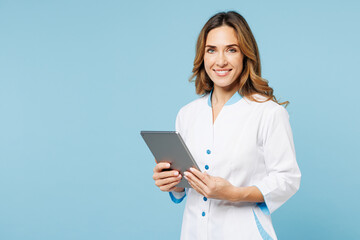 Female smiling happy cheerful doctor woman wear white medical gown suit work in hospital clinic office digital tablet pc computer isolated on plain blue background studio Health care medicine concept