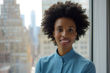 Afro woman smiling stands against window with blurred cityscape
