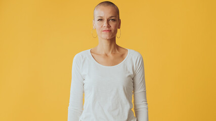 Hairless young woman looking at camera isolated on yellow background in studio