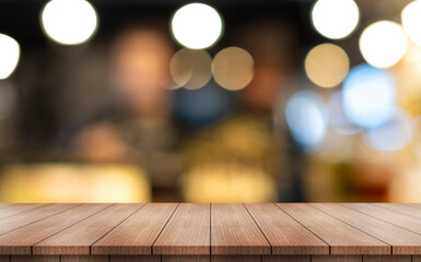 Empty wooden table top with lights bokeh on blur restaurant background.