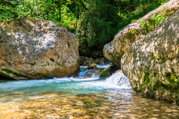 Naklejka na ściany i meble a mountain river with clear water, large rocks and water running between them