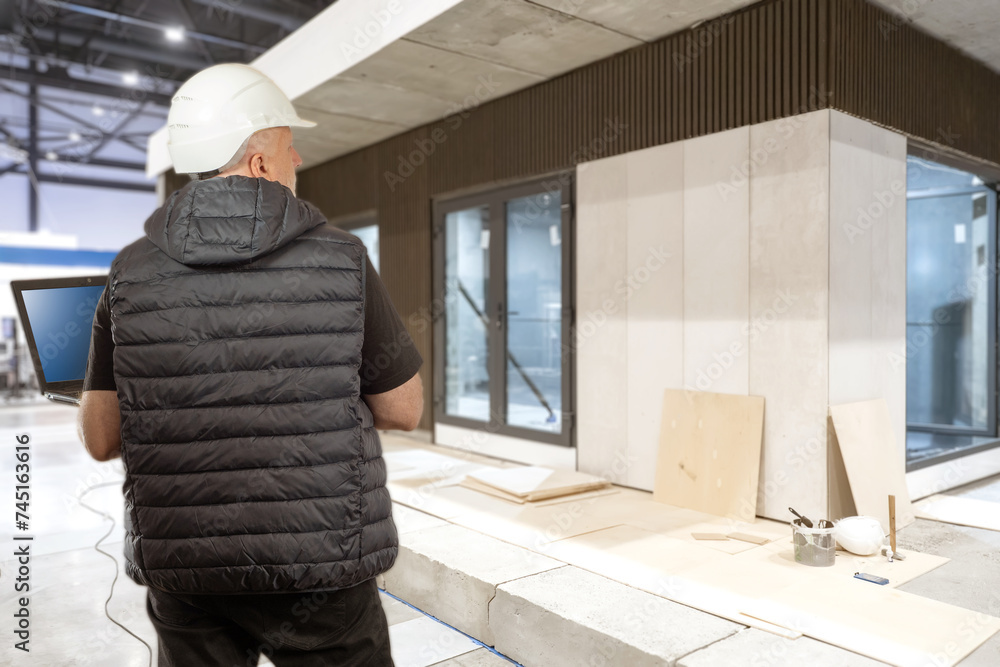 Aufkleber man with laptop near building under construction. foreman controls construction process. constructio