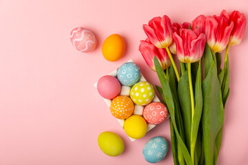 Easter eggs with a bouquet of tulips on a bright pink background. Easter celebration concept....