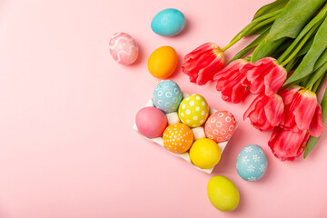 Easter eggs with a bouquet of tulips on a bright pink background. Easter celebration concept. Colorful easter handmade decorated Easter eggs. Place for text. Copy space.