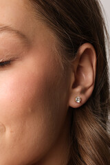 Beautiful young girl with fresh healthy skin. Woman advertise ear-rings. White background. Earrings closeup. Blond european woman with long hair with big lips, pretty smile. Cosmetology, scincare