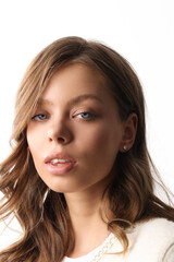 Fototapeta premium Beautiful young girl with fresh healthy skin. Woman advertise ear-rings. White background. Earrings closeup. Blond european woman with long hair with big lips, pretty smile. Cosmetology, scincare