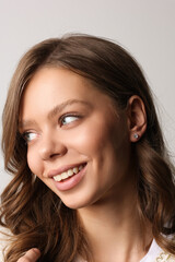 Naklejka premium Beautiful young girl with fresh healthy skin. Woman advertise ear-rings. White background. Earrings closeup. Blond european woman with long hair with big lips, pretty smile. Cosmetology, scincare