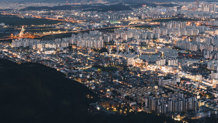 night view city lights urban sprawl illuminated streets high-rise apartment complexes dense housing patterns aerial perspective transportation arteries glowing urban grid infrastructure development 8k