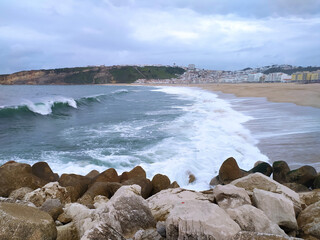 Ocean shore in stormy winter weather. Waves with splashes crash against the pier.