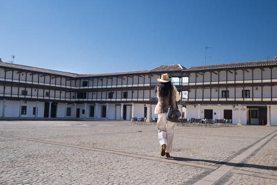 Middle aged female traveler walking on historical square Plaza Mayor of Tembleque in the Don Quixote rout in Spain on mobile phone.