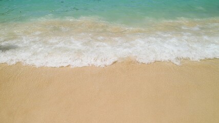 Fototapeta na wymiar Footage of small waves splashing on the sand beach with pebbles, nature background