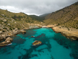 Mallorca, Cala Boquer beach, aerial drone view of torquoise water and rocks in the cloudy day