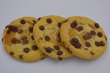 Sweets, delicious, large cookies with small pieces of milk chocolate arranged on a white background.