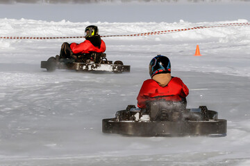 Karting driveres rides on an icy track on a winter day - obrazy, fototapety, plakaty