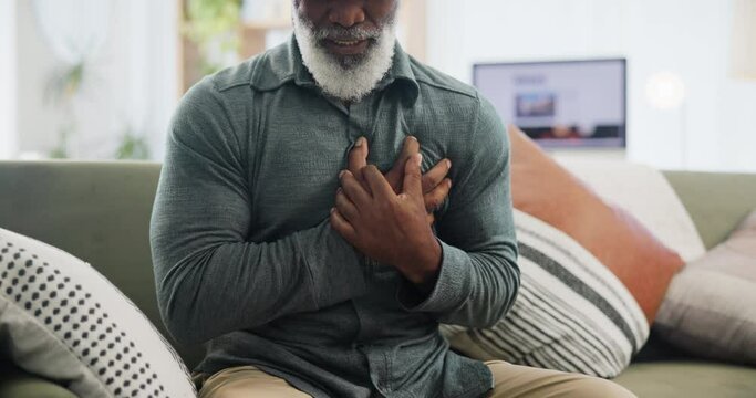 Heart attack, stress and senior man on a sofa with cardiac arrest, emergency or crisis in his home. Chest pain, anxiety or elderly African male with breathing problem, panic attack or heartburn issue