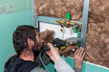 A skilled plumber joins polypropylene pipe with soldering machine in bathroom during installation...