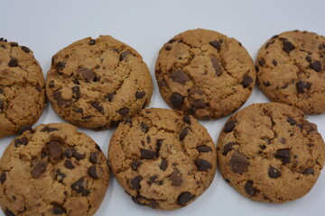 Sweets, delicious chocolate chip cookies with large chunks of milk and dark chocolate arranged on a white background.