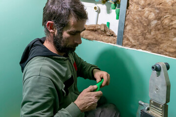 A skilled plumber joins polypropylene pipe with soldering machine in bathroom during installation...