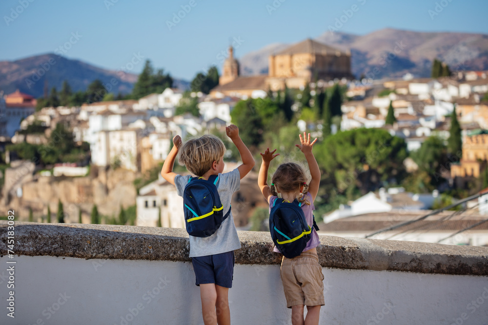 Wall mural kids stand on hill and lift hands next to panorama of ronda