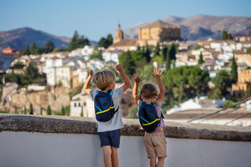 Kids stand on hill and lift hands next to panorama of Ronda - 745183082