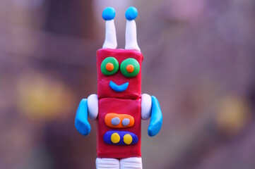 Naklejka premium A toy robot made of plasticine smiles.