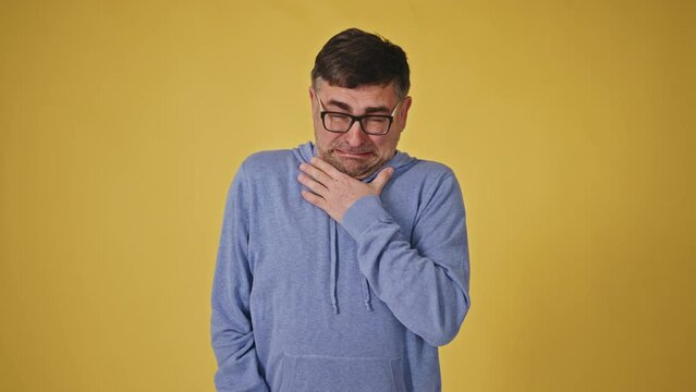Disgusted senior man with glasses on a yellow background showing repulsion and displeasure