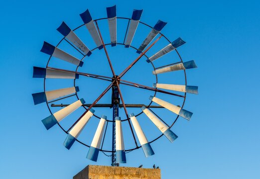 close-up view of a modern windmill with steel blades in the interior of Mallorca under a blue sky