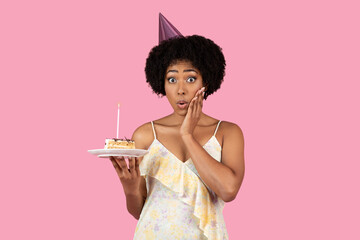 Shocked African American woman with curly hair wearing a party hat
