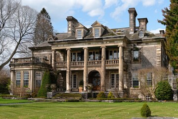 A grand stone house with towering columns and large windows, exuding elegance and historic charm in a picturesque setting