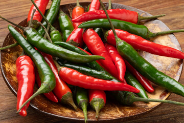 Bowl with whole fresh raw green and red rawit hot peppers close up  