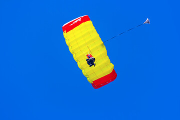 Man gliding down on a parachute in blue sky - 745202870