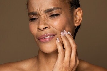 African american woman touching cheek in pain, grimacing