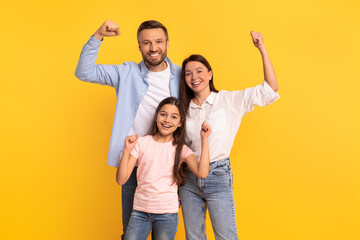 Fototapeta na wymiar Happy European Family Showing Biceps Over Yellow Studio Background