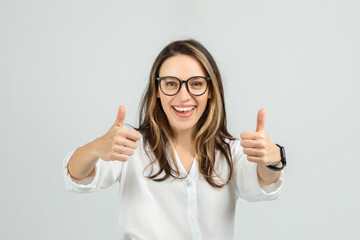 A smiling young woman with long hair and glasses gives two enthusiastic thumbs up