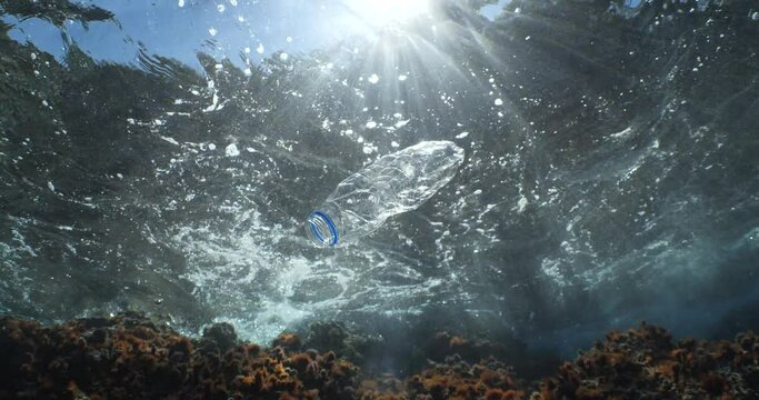 plastic bottle  underwater ocean pollution with sun beams and rays