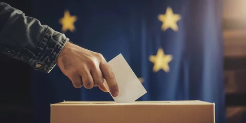 Fotobehang Unrecognizable man putting their vote in the ballot box with European Union flag on background. President governmental election giving your voice voting concept © Valeriia