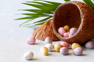 Colorful chocolate eggs in coconut shell, creative easter travel concept