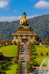 A series of steps leads towards a statue of Buddha located on the top of the mountain. The golden...