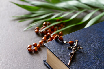 Bible with rosary and palm branch. Palm Sunday religious concept