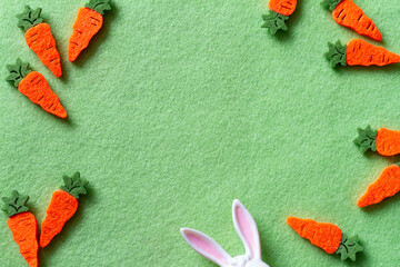 Composition with cute carrots and bunny ears on green background, easter concept