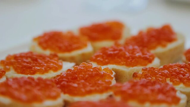 Delicious sandwiches with red caviar are on a plate on the festive table. Close-up food photography