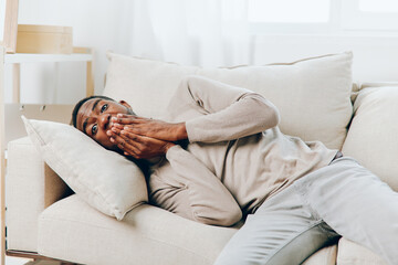 Obraz premium Stressed African American Man Suffering from Headache on Couch at Home