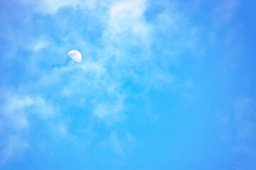 美しい青い空と白い雲と昼間の月
