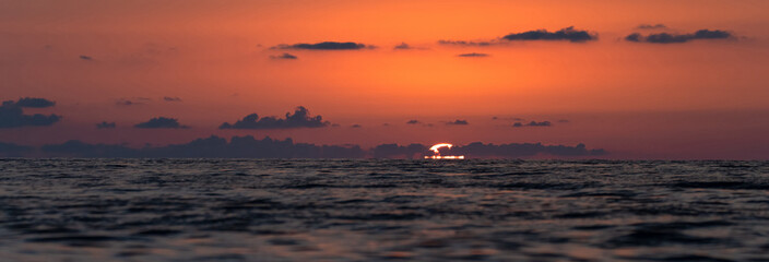 The red sun sets in the sea