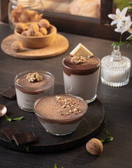 Chocolate cream dessert in bowls on a wooden table against the background of a window and flowers