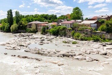 Fototapeta na wymiar Rioni river in Kutaisi, landscape view with white stones and residential houses on the river bank, view from White Bridge, summer, Georgia.