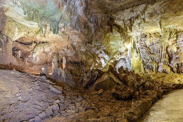 Prometheus Cave Natural Monument - largest cave in Georgia with hanging stone curtains, stalactites and stalagmites, colorful illuminated rock formations and tourist path.