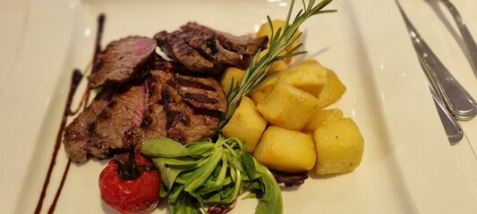 Juicy sliced steak paired with roasted potatoes and fresh greens, plated beautifully